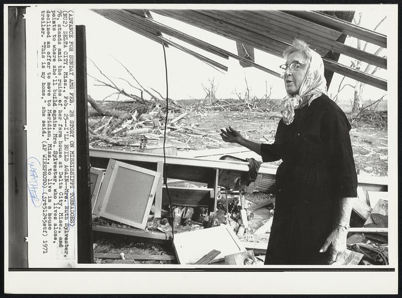 I'll Build Again--Mrs. Ruth Sylvester, 76, stands amid the ruins of her farm house at Delta City, Miss., and points to where she'll build again. Mrs. Sylvester, who lives alone, declined an offer to move to Meridian, Miss., to live in a house trailer. "This is my home," she said.