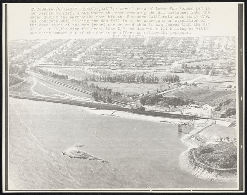 Aerial view of Lower Van Norman Dam in San Fernando, Calif. shows where the road crossing the dam collapsed into the water during the earthquake that hit the Southern California area early 2/9. The concrete wall holding the dam fell into the water, and an evacuation of the area south of the dam (rear) was ordered when it was feared that the dam would let go, flooding the area. Late 2/9 the dam was still holding as water was being pumped out of the dam in an effort to relieve the pressure.