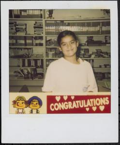 Girl smiling in front of wall of VHS tapes