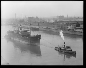 Bull line sugar boat SS Evelyn towed up Fort Point Channel by the tug Leader, alongside the South Station power house
