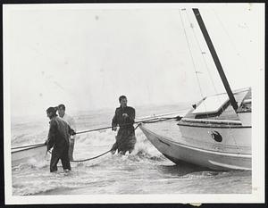 Surf was Rising -- Even men like these who were out early found it rough going in the surf as they hauled on lines to pull this craft ashore.