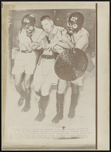 Riot Casualty--Injured Hong Kong police officer is aided by two gas-masked fellow policemen during renewed rioting in the British colony on Red China's border last night. Communist-led strikes today crippled the crown colony's public transport.