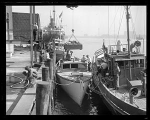 Supplies being loaded onto boat surrounded by Coast Guard vessels