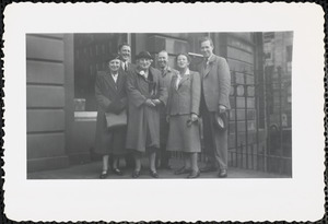 Three men and two women stand outside what appears to be the façade of a large building