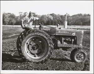 Man sitting on Farmall tractor in plowed field