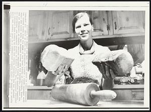 Staff of Life for Engineer's Family- Janet Liessner with two loaves fresh from the oven of her home bakery in Carlisle, Mass., where she lives with her husband Walter and six children. Liessner was one of thousands of highly skilled engineers fired in massive layoffs in electronic and research plants in Boston area. Mrs. Liessner expanded an informal home bakery to ease the family finances. Now her husband sells her bakery good in a century-old country he bought in nearby Acton.