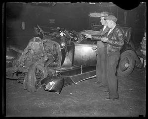 Two men stand examining a damaged car