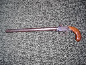 Pistol with rounded wood grip and long barrel