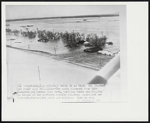 Highest Water in 42 Years Rip Tracks and Sweep Away Buildings -- The muddy Missouri tour into Bismarck and Mandan this week, tumbling homes and ripping up tracks of the Northern Pacific railroad main-line embankment. Fence-like posts are railroad ties on end.