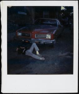 Young man lying down next to car