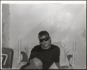 Young woman in sunglasses sitting on a bed