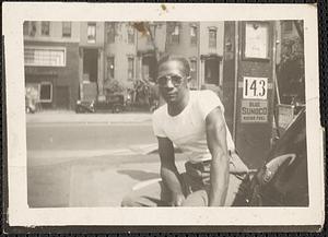 Man wearing sunglasses sits near a gas station pump