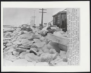 Storm Aftermath--A bulldozer was needed to clear this road, on the shore of Halifax harbour, of these large ice-cakes swept up on shore by a blizzard that ripped across the Canadian Maritimes over the week-end. At least two persons are dead and ten missing after a week of storms and blizzards.