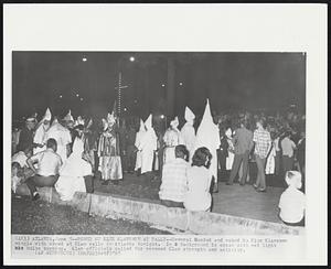 Robed Ku Klux Klansmen at Rally--Several Hooded and robed Ku Klux Klansmen mingle with crowd at Klan rally in Atlanta tonight. In background is cross with red light bulbs burning. Klan officials called for renewed Klan strength and activity.