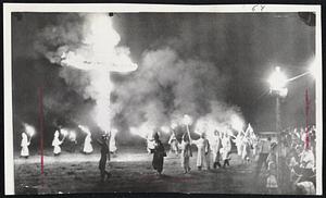 Hooded Ku Klux Klansmen, led by a special security guard, formed a circle around a blazing 25-foot cross at a KKK rally near Salisbury, N.C. About 2,000 persons attending the rally heard Imperial Wizard Robert M. Shelton of Tuscaloosa, Ala., blame the current civil rights movement on Communists.