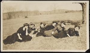 Six young women reclining in a field