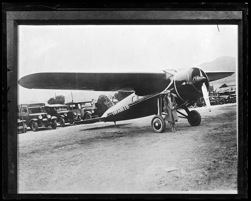 Amelia Earhart posing beside plane
