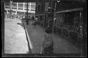 Children on a sidewalk, women in the background