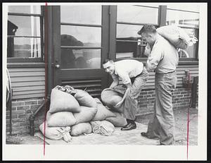 Sandbagging Doors - H. J. Szkotnicki, left, and R. A. Bahr, right, pile sandbags at door of U.S. Naval Training Center in Salem to prevent flood waters from overflowing in water-level building.
