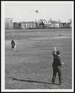 Kite Flying Weather and Arthur Chapin of Boston demonstrated for young Miss along the Charles River bank as spring weather continued yesterday.
