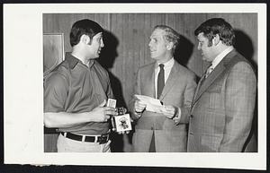 Bruins' star Johnny (Chief) Bucyk presents a Klondike lighter to Mayor Kevin White. The lighter is a gift from Mayor Iverton of Edmonton, Alberta, Canada, Bucyk's hometown. Mayor Iverton also invited Mayor White to attend the Klondike Day Celebrations in Edmonton in July. Looking on is Larry Messier, a school trustee from Edmonton and a representative of Mayor Iverton.