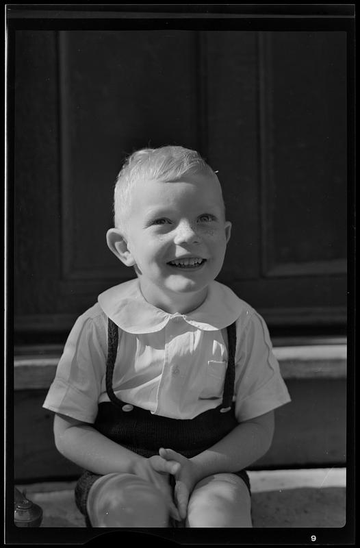 Boy on porch steps, smiling