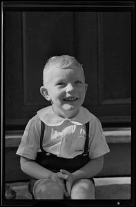 Boy on porch steps, smiling