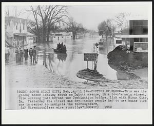 Picture of Gloom--This was the gloomy scene looking south on Dakota avenue, this town's main street, this morning just beyond the Combination bridge, link with Sioux City, Ia. Yesterday the street was dry--today people had to use boats like one in center to navigate the thoroughfare.