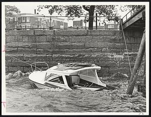 Below, a pleasure boat is partially submerged at the South Boston Yacht Club.