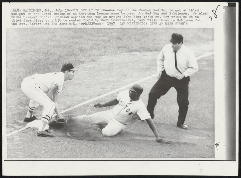 Baltimore, Md. – Cut Off At Third – Joe Foy of the Boston Red Sox is out at third tonight in the first inning of an American League game between the Red Sox and Baltimore. Orioles third baseman Brooks Robinson applies the tag as umpire John Rice looks on. Foy tried to go to third from first on a hit to center field by Carl Yastrzemski. Paul Blair threw to Robinson for the out. Boston won the game 6-4.