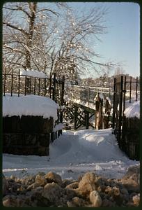 Snow on road and fence, open gate in center