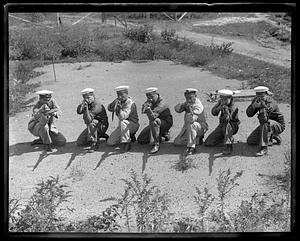 A row of men in uniform, some wearing caps which read A.R.A. Rivadavia, kneel holding rifles in firing position