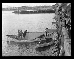 Men on a Coast Guard boat looking in the water in front of a crowd