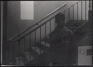 Young man standing by a stairwell and wearing a baseball hat and jacket