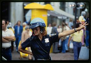 Woman motorcycle cop directs traffic wearing crash helmet, Haymarket Square, Boston