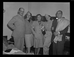 Mixed gender group standing in bedroom, some in uniform