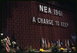 Stage sign reading "NEA 1961 A Charge to Keep"