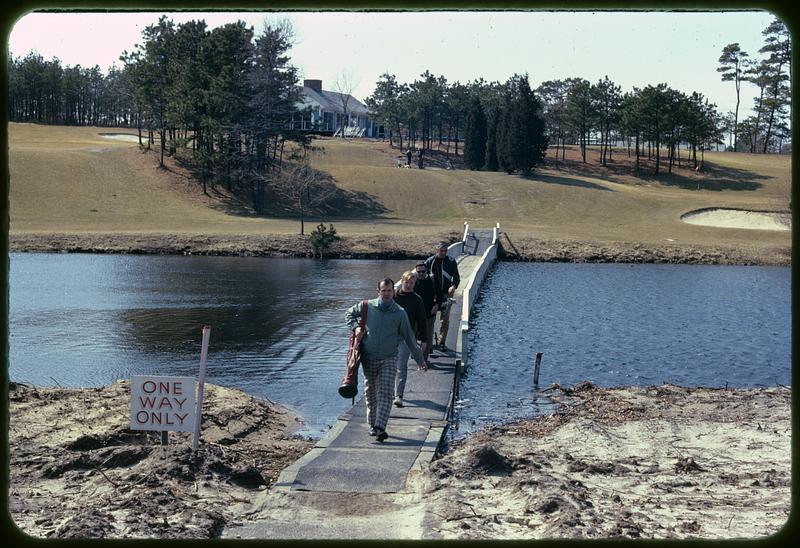 Golfers crossing footbridge over water