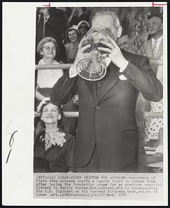 Man-Sized Snifter for Acheson-- Secretary of State Dean Acheson quaffs a hearty toast in German wine after laying the foundation stone for an American memorial library in Berlin Sunday. Mrs. Acheson, who is accompanying the U.S. diplomat on his current European tour, smiles at lower left.