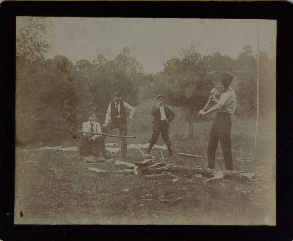 Man chopping wood while friends watch