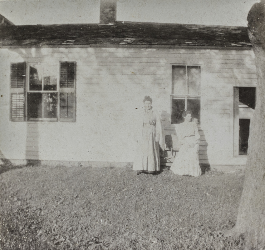 Two unidentified women in front of house wing, 114