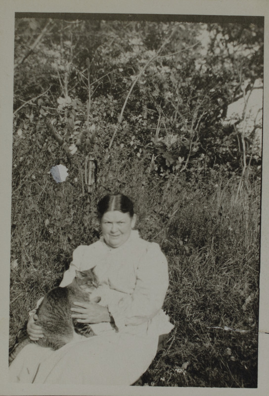 Unidentified woman in garden holding cat, 123