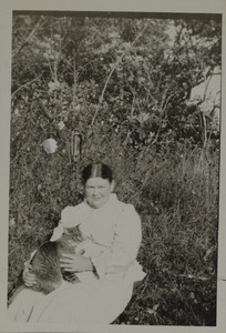 Unidentified woman in garden holding cat, 123