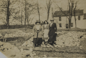 Three women, a house, and some rocks