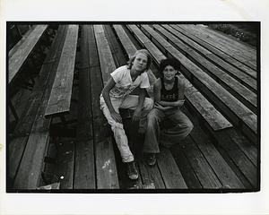 Two teenagers pose on bleachers