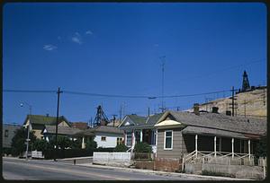 Street with houses in front of hill with mine head frames, Butte, Montana