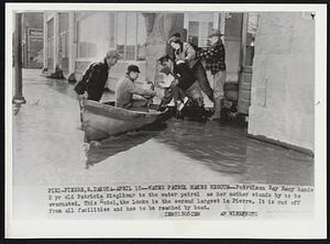 Water Patrol Makes Rescue -- Patrolman Ray Racy hands 2 yr old Patricia Sieglhour to the water patrol as her mother stands by to be evacuated. This Hotel, the Locke is the second largest in Pierre. It is cut off from all facilities and has to be reached by boat.