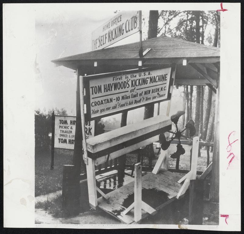 Ione kicks the old self-kicking machine, invented several years ago and a national tourist attraction in New Bern, N. C. Machine is for people who want to kick themselves. Machine was lifted from house and damaged by hurricane.