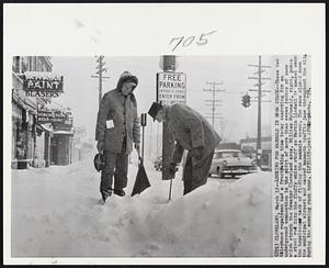 Cleveland -- Looking For Manhole In Snow Stack -- These two telephone repairmen had a frustrating time today searching for an underground connection in the midst of more than seven inches of snow which struck the Greater Cleveland area. William McDonald, right, pokes a steel rod into the fluffy white stuff as Martin Lindahl is amused over the hopeless task of finding the manhole cover. The snow closed down the municipal airport and caused mammoth traffic jams throughout the city during the morning rush hour.