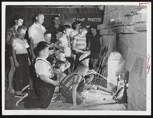 Toasting Marshmallows is part of the fun provided for infantile paralysis victims at their camp on Plum Island. Camp director Patrick Murnane supervises the proceedings.